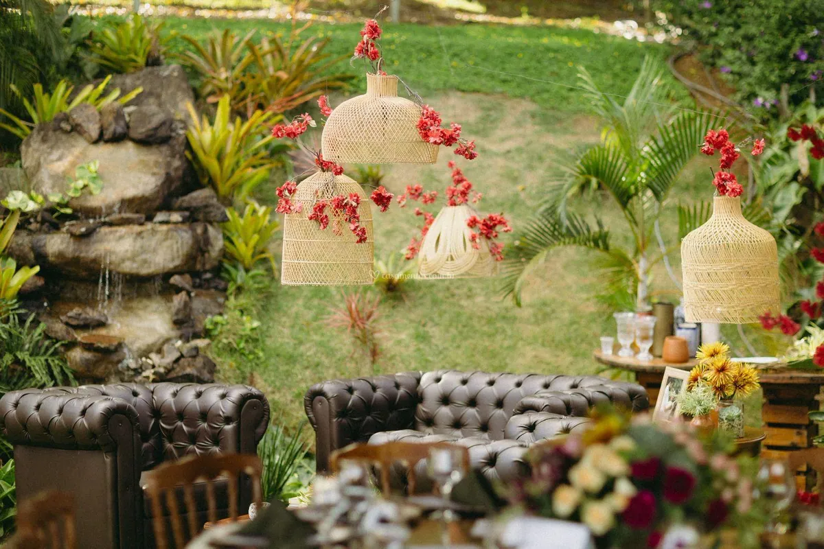 Lounge com sofás de couro no jardim, entre plantas e luminárias de palha