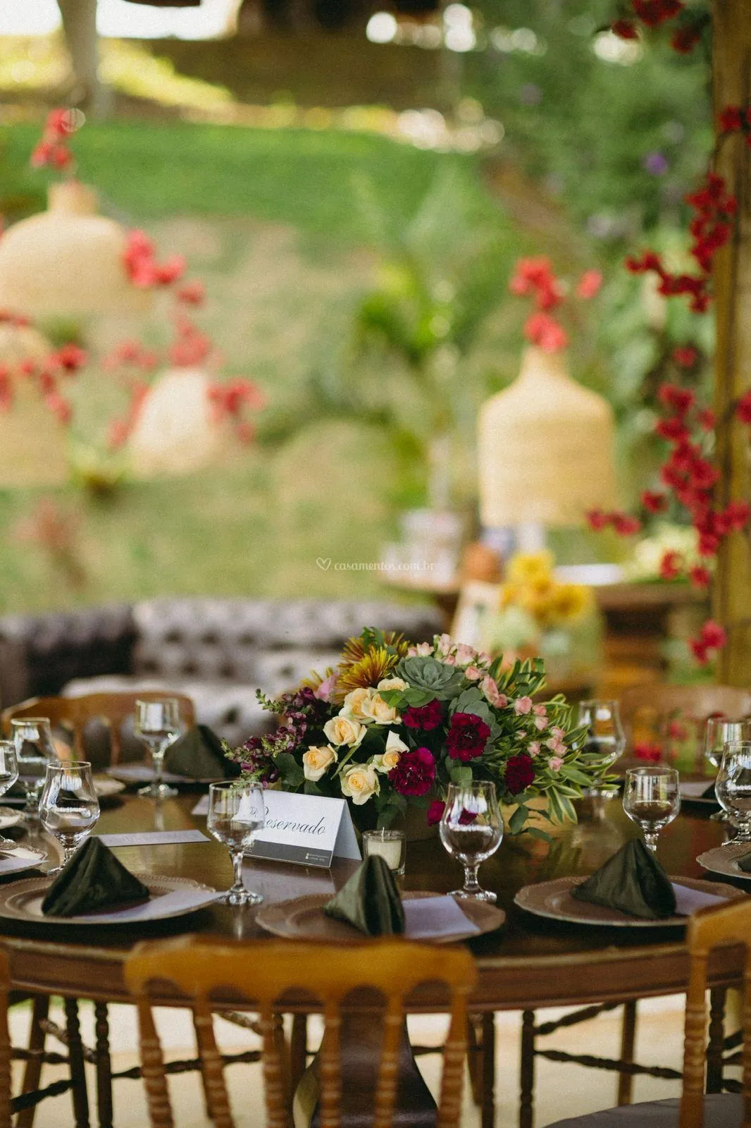 Luminárias de palha com flores vermelhas sobre mesa redonda decorada